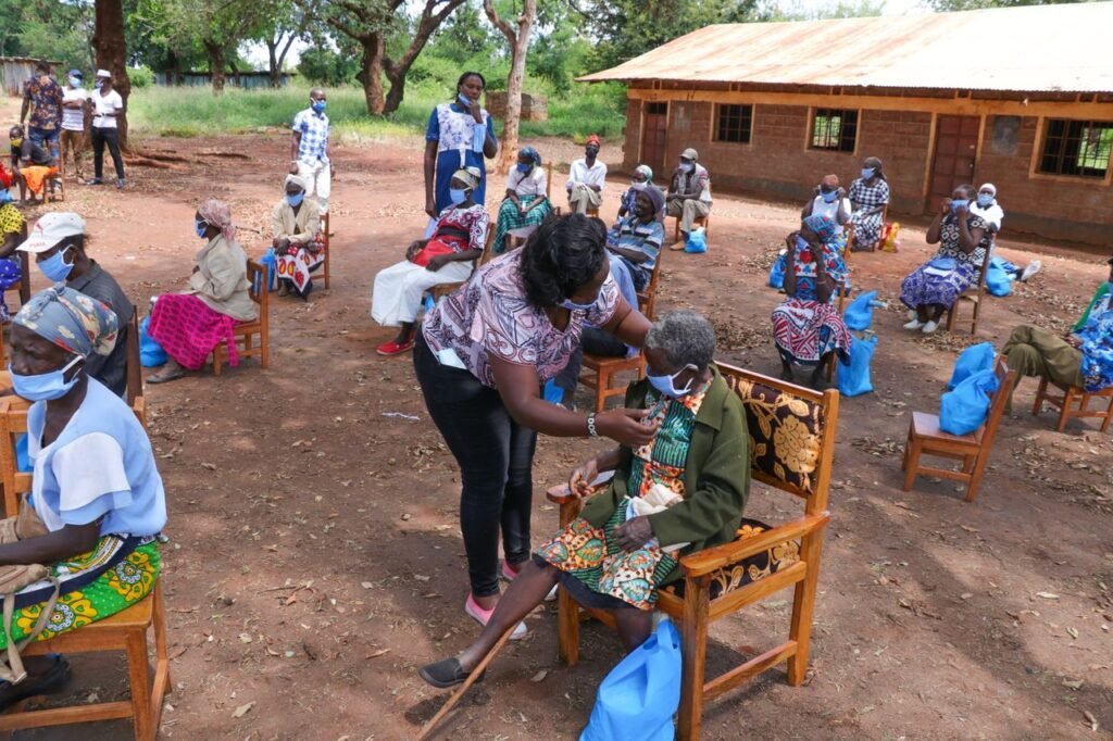 Mastering the First Impression: Your intriguing post title goes here High angle of anonymous African female taking care of senior people in face masks sitting on chair near shabby building of nursing home in village